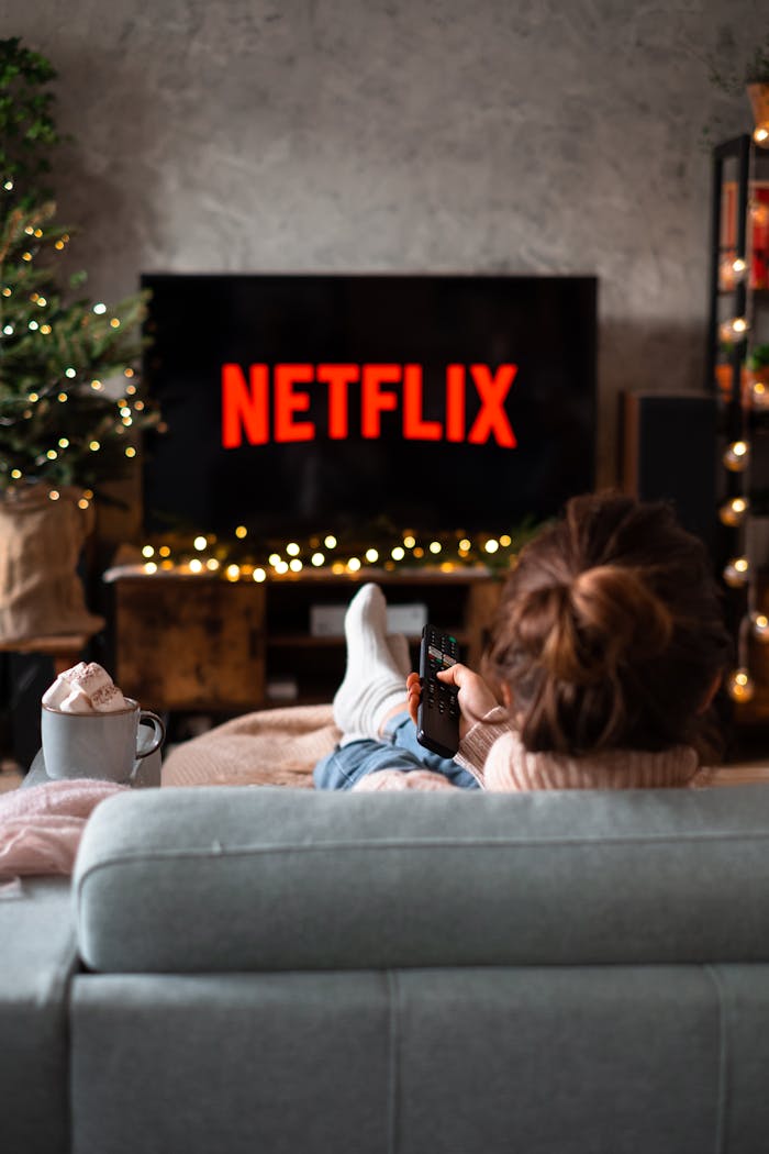 Woman relaxing on sofa with hot chocolate and Netflix on a winter evening.