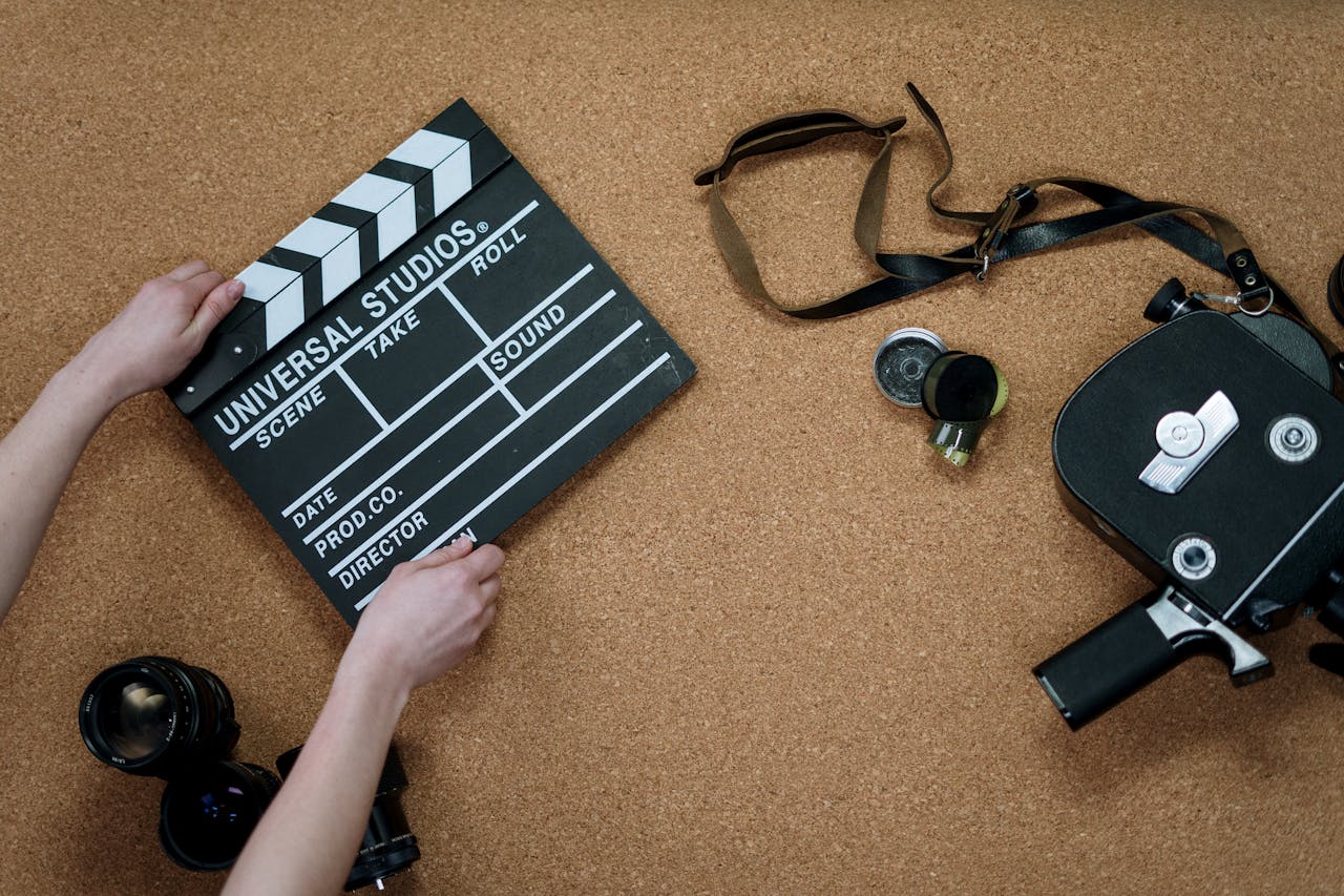 Top view of classic filmmaking tools including a slate and vintage camera on a cork surface.